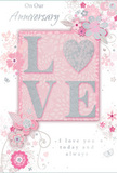 This anniversary card is portrayed in close-up, revealing every tender detail of its romantic design, which feels perfectly at home in the calm, leafy character of Kingston Vale. The main focal point is the word "LOVE," placed at the centre in soft, raised lettering, each curve and edge coated with a fine, shimmering glitter that suggests both celebration and intimacy. The letterforms stand on a panel of blush pink that glows subtly against a paler pink and white background, creating a layered effect, as though the sentiment itself is gently cradled. Surrounding this central word, delicate illustrated flowers and airy vines unfurl with an almost watercolour softness. The blooms, in tones of blush, mauve, and pearly white, are outlined with fine lines and shaded just enough to hint at depth, like a florist's thoughtful sketch before arranging a hand-tied anniversary bouquet for a Kingston Vale home near Richmond Park or along Kingston Hill. Subtle silvery accents touch petals and swirls, catching the light but never overwhelming the gentle palette. Tiny flourishes-curving stems, petite leaves, and whimsical details-lend movement to the design, reminiscent of petals drifting gently on a spring breeze across a garden in nearby Coombe. Elegant script phrases, including anniversary wishes and a quiet declaration of ongoing love, are woven into the composition, the lettering slim and graceful. The mood of the card is soft, intimate, and enduring, like a whispered promise shared over many years. It feels like the perfect companion to a vase of pastel roses delivered locally-a keepsake that honours both memory and the future still to come.